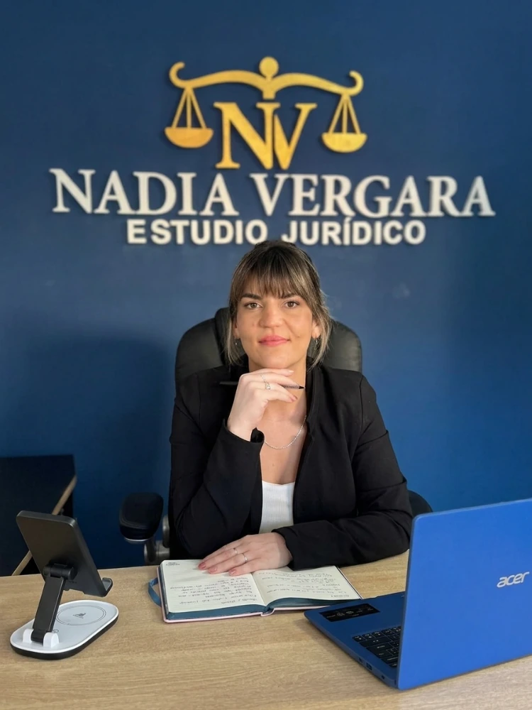 Nadia Vergara en su estudio jurídico, con el isotipo profesional al fondo